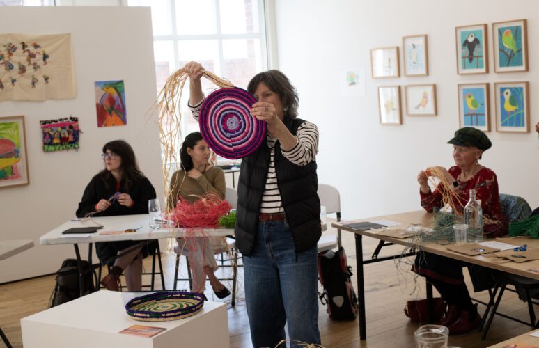 Stacey Edwards holding up her woven basket for participants to see