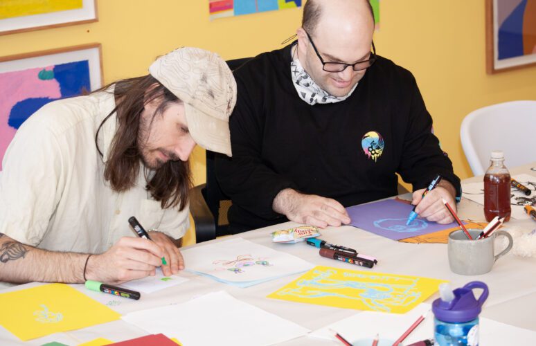 Artist Adrian Lazzaro drawing at a table during the People Of Honour workshop at the APA gallery