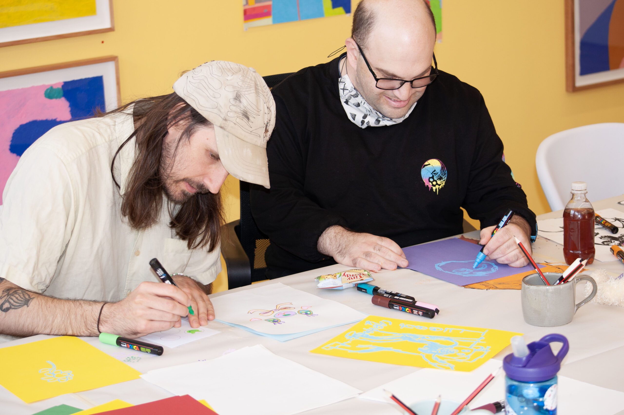 Artist Adrian Lazzaro drawing at a table during the People Of Honour workshop at the APA gallery